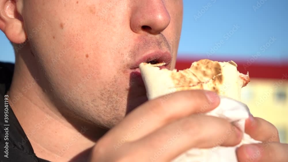 The fat man is eating shawarma. Close-up of the lips of a fat man who eats harmful and tasty shawarma outside on a sunny day The fat man is eating shawarma. Close-up of the lips of a fat man who eats harmful and tasty shawarma outside on a sunny day