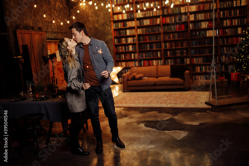 Beautiful couple kissing, hold sparklers in arms, adorable wife and charming husband enjoy festive mood, cozy winter holidays at home, New Year and Christmas celebration concept © shunevich