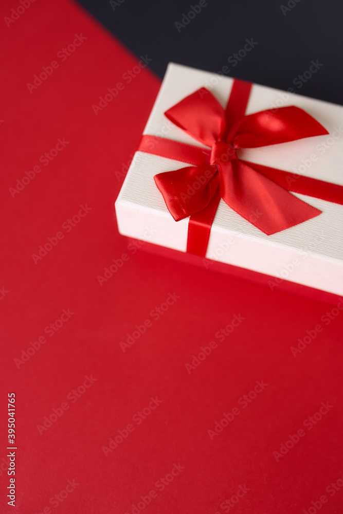 White present with red ribbon on the bright red background White present with red ribbon on the bright red background