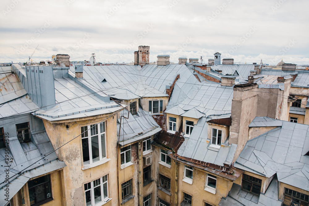 Iron roofs of houses in old city on cloudy day. Top view of houses of St. Petersburg. Horizontal photo. Iron roofs of houses in old city on cloudy day. Top view of houses of St. Petersburg. Horizontal photo.