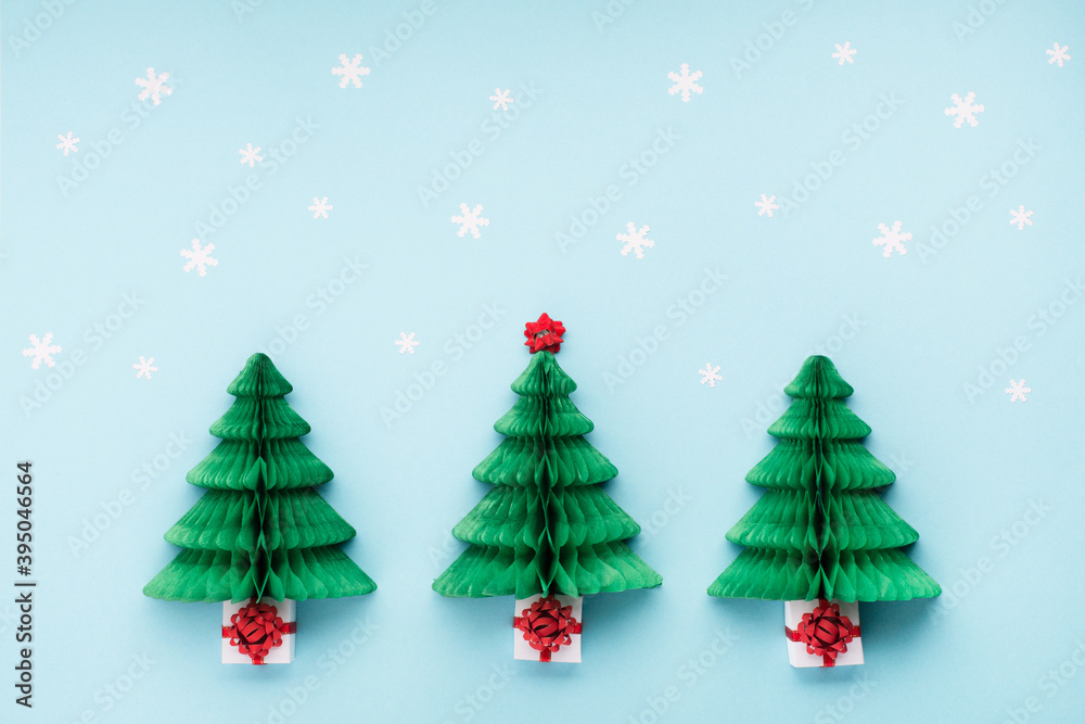 Christmas card - Xmas paper green tree, snowflakes and gift boxes on blue background.
