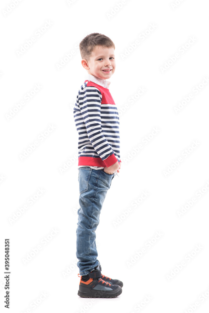 Side view of cute happy young boy smiling and looking at camera with hands in pockets. Full body portrait isolated on white background. Side view of cute happy young boy smiling and looking at camera with hands in pockets. Full body portrait isolated on white background.