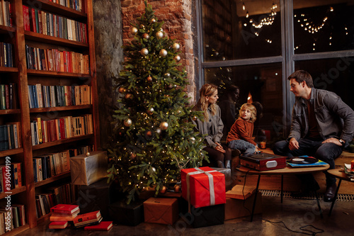 Lovely family sit near decorated Christmas tree with presents, enjoy festive mood, caring father with loving mother spend with preschooler son winter holidays, new year concept © shunevich