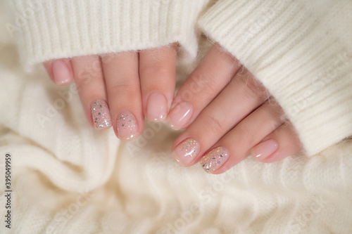 Closeup top view flatlay photography of beautiful elegant manicured female hands isolated on fluffy soft white texture of cozy sweater.