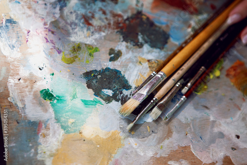 brushes of different sizes are on the palette of colors from the artist