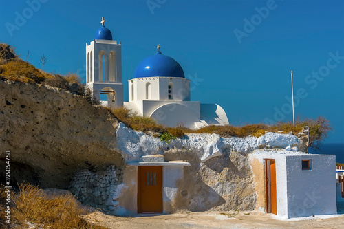 A small local church with a blue dome outside the village of Oia, Santorini in summertime