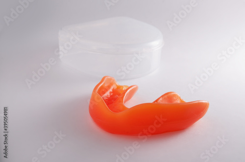 Orange mouthguard with transparent case on the white background
