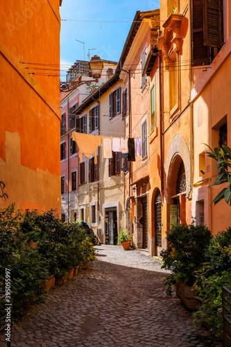 Fototapeta Naklejka Na Ścianę i Meble -  Picturesque Small Cobblestone Alley in Trastevere with Tradional Colorful Houses - Rome, Italy.