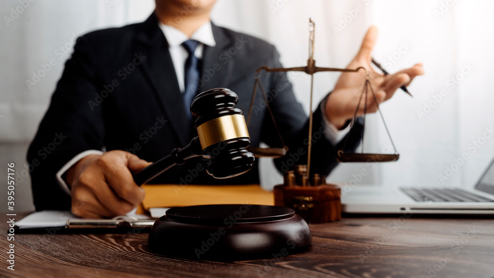 Justice and law concept.Male judge in a courtroom with the gavel, working with, computer and docking keyboard, eyeglasses, on table in morning light Justice and law concept.Male judge in a courtroom with the gavel, working with, computer and docking keyboard, eyeglasses, on table in morning light