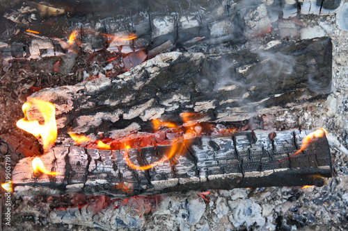 Glowing embers in hot red color  abstract background. The hot embers of burning wood log fire. Firewood burning on grill. Texture fire bonfire embers.