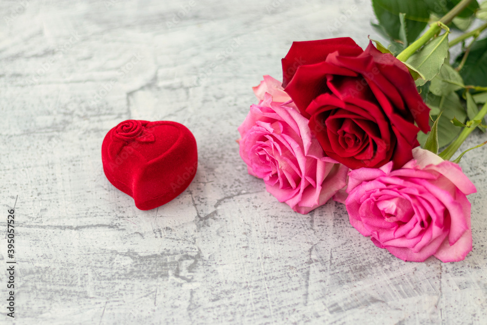 Red velvet box for engagement ring next to a bouquet of rose with space for text. Romantic gift for Valentine's day. Love and marriage proposal concept. Copy space Red velvet box for engagement ring next to a bouquet of rose with space for text. Romantic gift for Valentine's day. Love and marriage proposal concept. Copy space