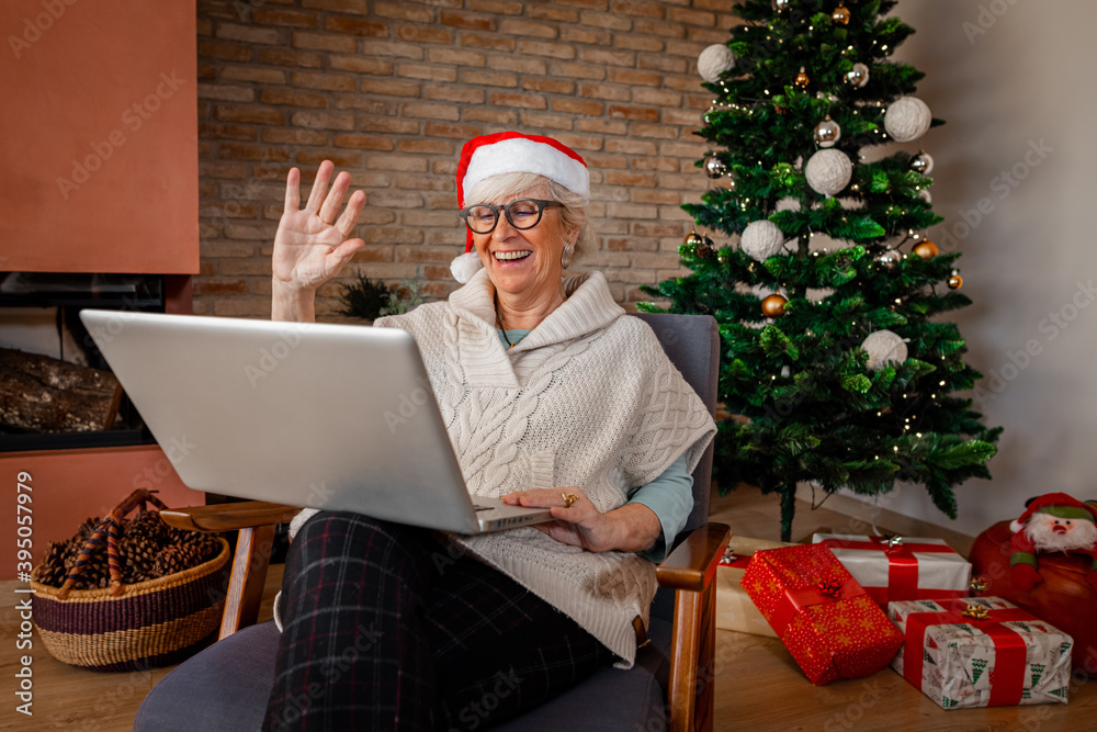 Happy laughing senior woman at home, with computer having video call and waving hands at home. Christmas, holidays, online communication, Social distance, self isolation, quarantine concept. Happy laughing senior woman at home, with computer having video call and waving hands at home. Christmas, holidays, online communication, Social distance, self isolation, quarantine concept.