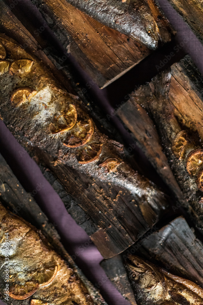 Smoked fish on a wood plank on a purple tablecloth Smoked fish on a wood plank on a purple tablecloth