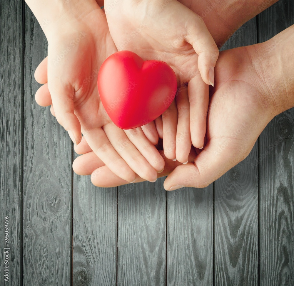 Man and woman holding red heart on background Man and woman holding red heart on background