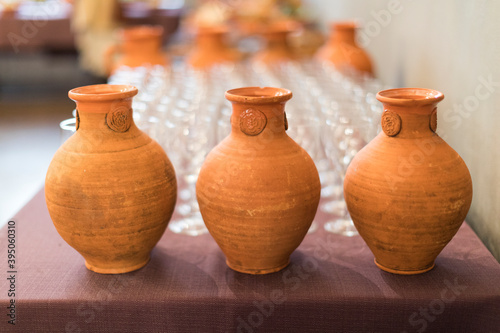 Multiple clay pitchers with glasses in the background