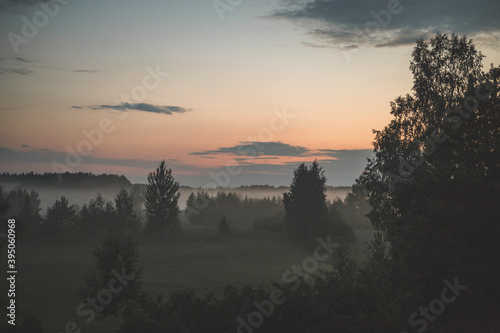sunset over a field and forest foggy weather mist 
