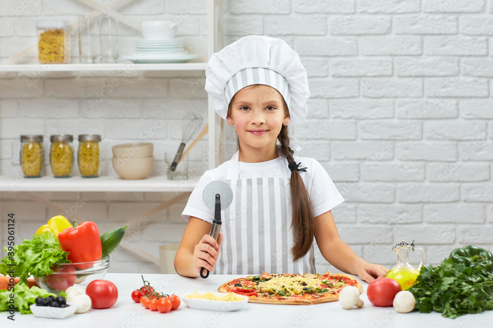 cute little girl in chef hat and an apron holding pizza knife in the kitchen cute little girl in chef hat and an apron holding pizza knife in the kitchen