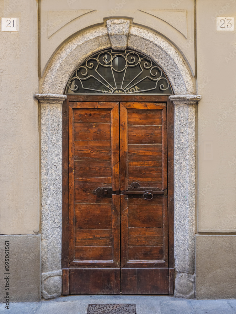 ancient arched wooden door with large bolt, metal decorations and stone frame. ancient arched wooden door with large bolt, metal decorations and stone frame.
