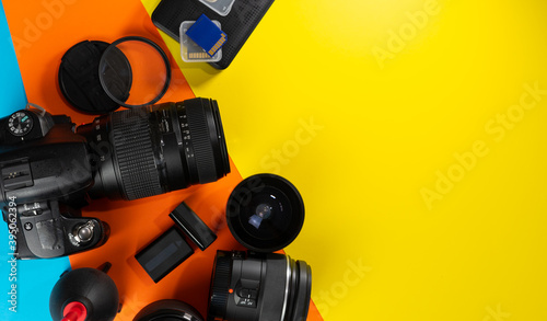 Top view of photo accessories. A camera that focuses on the right, other lenses, a hard drive, memory cards and batteries.
