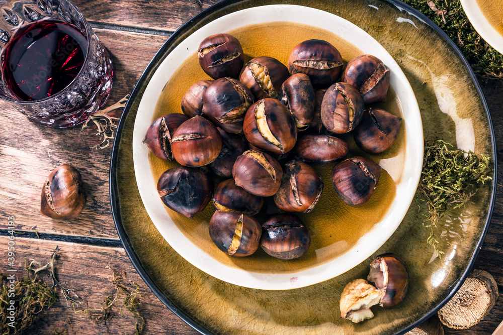 Roasted chestnuts for Christmas served on a wooden table with red mulled wine Roasted chestnuts for Christmas served on a wooden table with red mulled wine