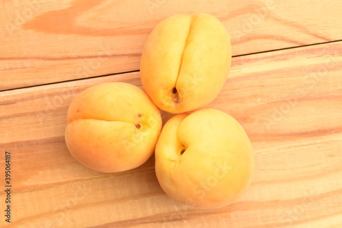 Several ripe yellow pineapple apricots, close-up, on a wooden table.