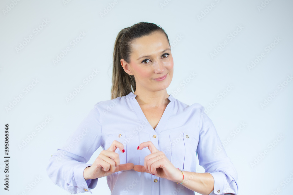 Portrait of lovely woman making heart form with her hands smiling wearing casual shirt isolated over white background