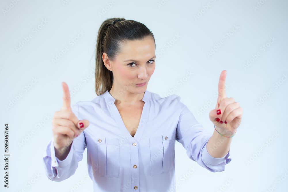 Smiling beautiful woman pointing up and looking at the camera over white background Smiling beautiful woman pointing up and looking at the camera over white background
