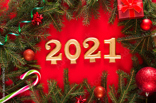 Happy New Year 2021. Golden digits 2021 with christmas decor are on red background. Holiday Party Decoration or postcard concept with top view © ribalka yuli