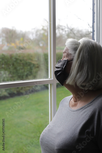 Woman with black mask on her face is looking at window during corona virus time. © Olesia Prokoshina