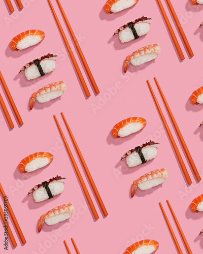Pattern of sushis or niggiris with orange chopsticks over a pink background