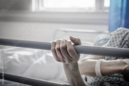 Dłonie starszej osoby na łóżku szpitalnym