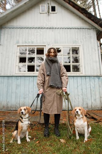 young stylish woman with two beagle dogs in the forest