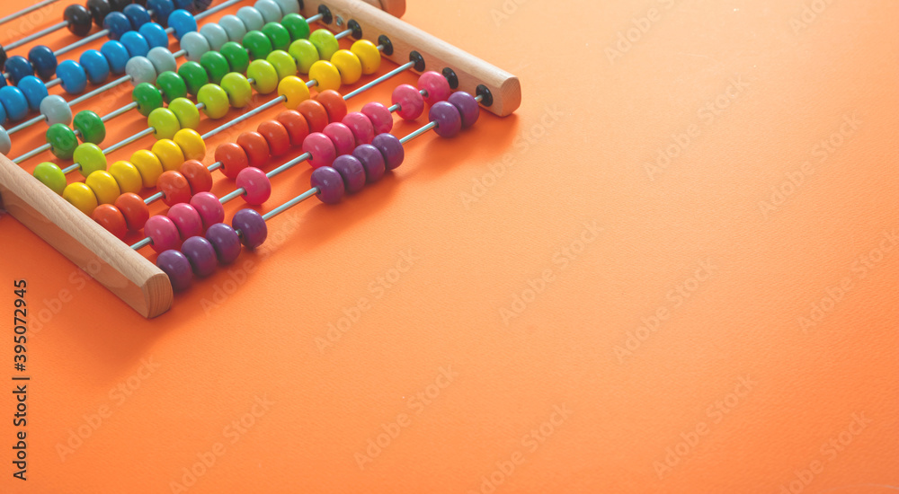 Obraz premium School abacus with colorful beads on orange color background, close up view