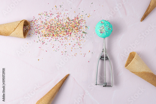 Fotografi Spoon with a smurf ice cream and some wafer cones and topping on a pink background