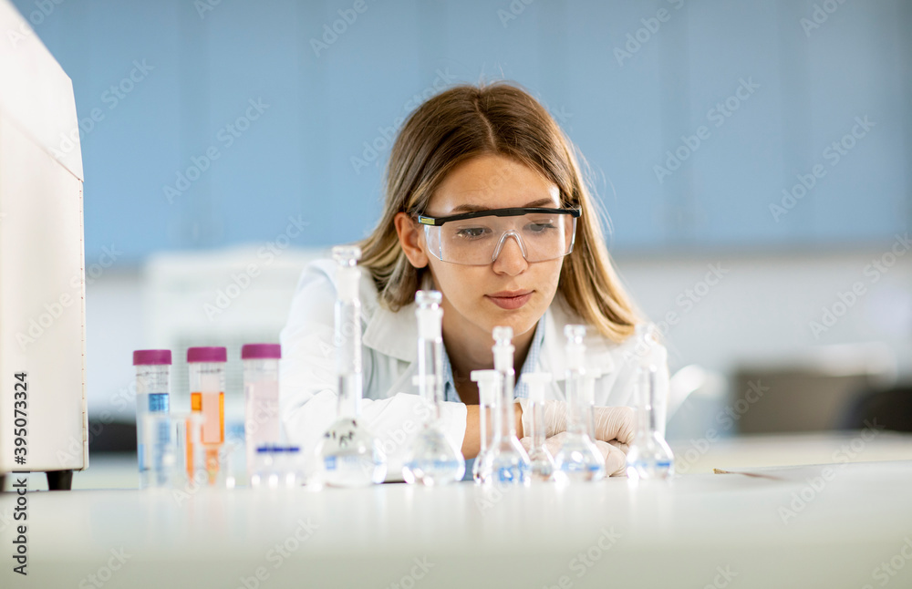 Female medical or scientific researcher looking at a flasks with solutions in a laboratory Female medical or scientific researcher looking at a flasks with solutions in a laboratory