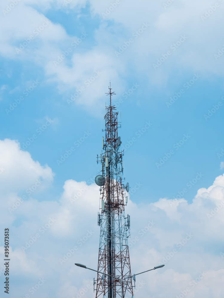 Communication pole on blue sky with group of white clouds background, with the top of the light pole in front Communication pole on blue sky with group of white clouds background, with the top of the light pole in front