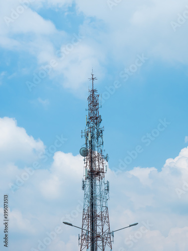 Communication pole on blue sky with group of white clouds background, with the top of the light pole in front