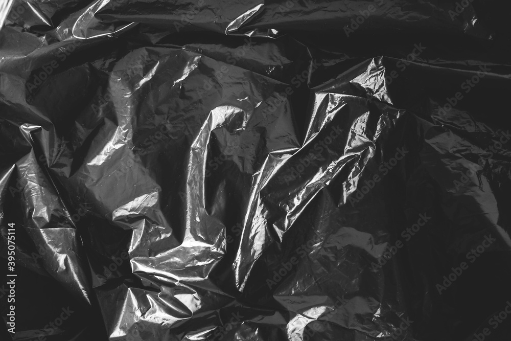 Black crumpled plastic film as a background texture image. Top view. Copy, empty space for text