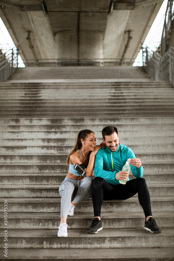 Young couple resting during training with bottle of water Young couple resting during training with bottle of water