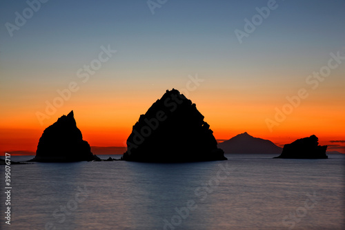 LEMNOS ISLAND, NORTH AEGEAN, GREECE. Sunset at Avlonas beach, very close to Myrina, the capital town of the island. The little volcanic islets are called "Nissoudia". In the background, Mount Athos.