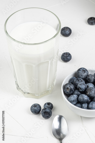 flat lay on a white background. A glass of milk and a bowl of blueberries. Morning breakfast. Free space for text labels and advertisements