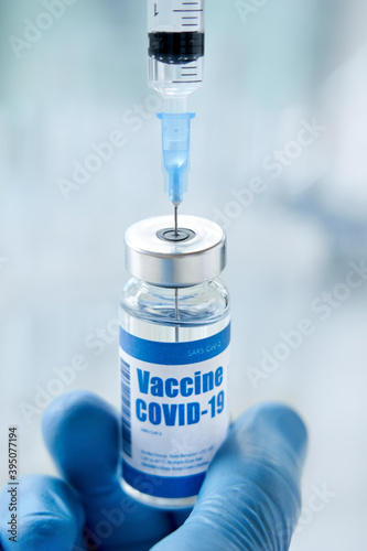 Male doctor scientist hand wears medical glove holding vial with covid 19 cure taking corona virus vaccine dose in syringe from medical bottle preparing for injection. Coronavirus flu drug vaccination