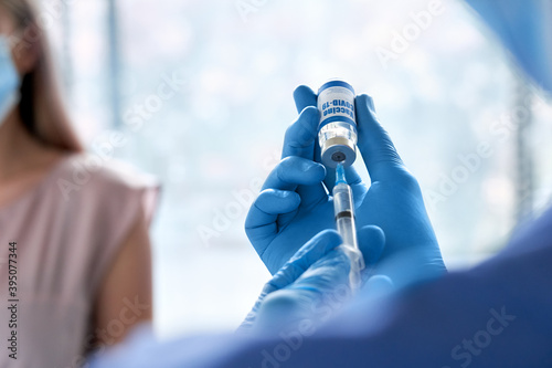 Fototapete Male doctor wearing gloves holding syringe taking coronavirus vaccine dose from vail preparing for covid 19 vaccination for patient