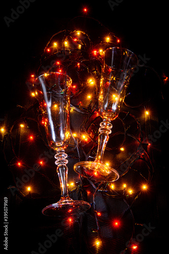 Champagne glasses are on a garland. New Year card. Glowing garland. Glasses. Glasses for sparkling wine.