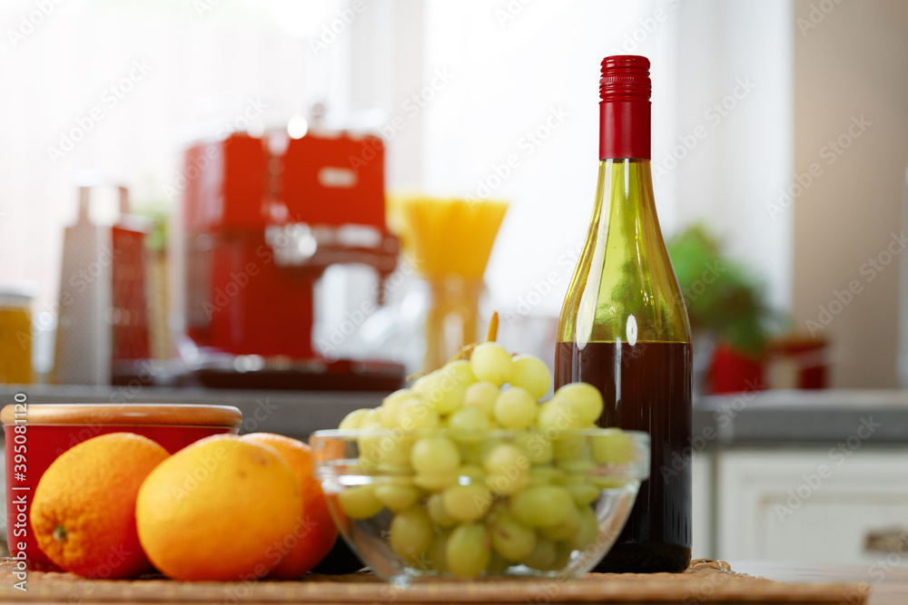 Bottle of red wine with grapes and oranges on kitchen table Bottle of red wine with grapes and oranges on kitchen table