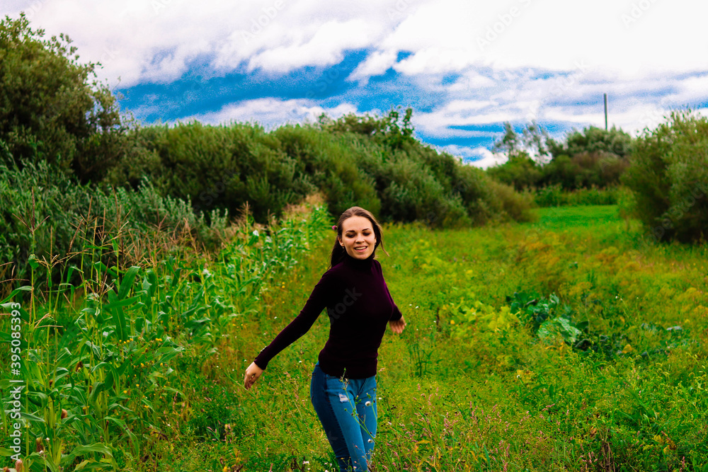 beautiful brunette girl in purple golf near a green bush with a flower in her hair dances and laughs beautiful brunette girl in purple golf near a green bush with a flower in her hair dances and laughs