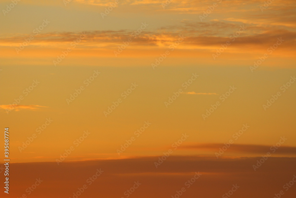 Sun below the horizon and clouds in the fiery dramatic orange sky at sunset or dawn backlit by the sun. Place for text and design