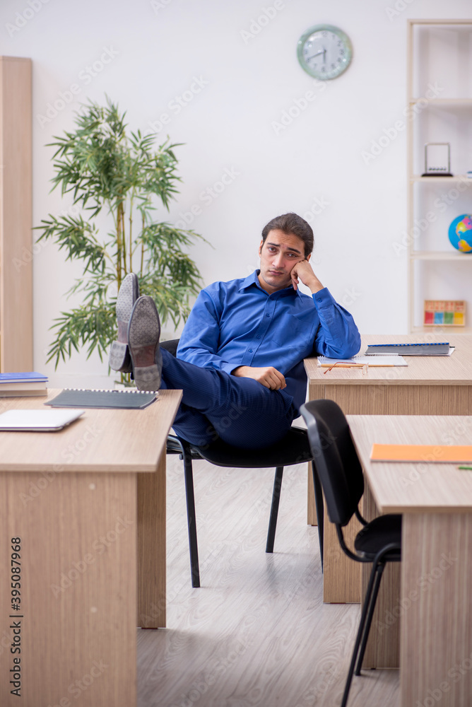 Young male teacher being tired in the classroom Young male teacher being tired in the classroom