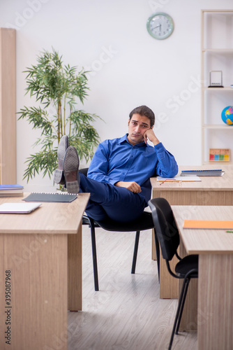 Young male teacher being tired in the classroom