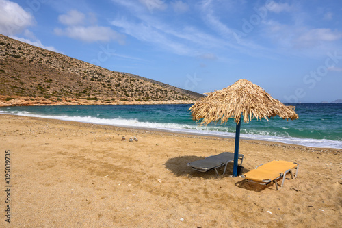 Sun beds and umbrellas at Agia Theodoti beach on Ios Island. A wonderful beach with the golden sand and azure waters. Cyclades  Greece